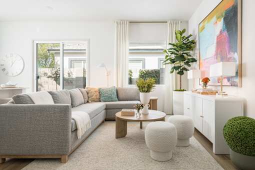 A living room with a grey sofa, a white coffee table, and a large painting on the wall.