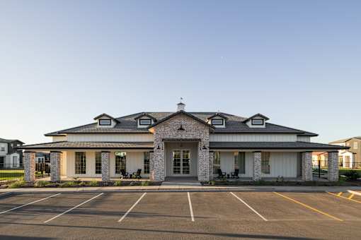 A white building with a parking lot in front.