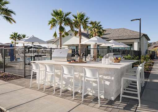 A white table with chairs is set up outside with a house and palm trees in the background.