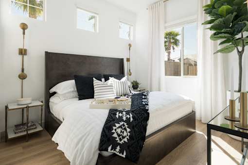 A bedroom with a large bed and a plant on the side table.
