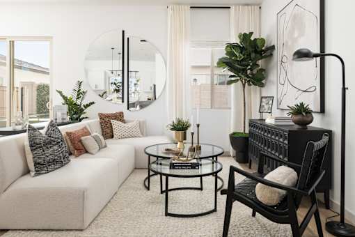 A living room with a white sofa, a black chair, and a glass coffee table.