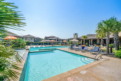 A large swimming pool surrounded by lounge chairs and palm trees.