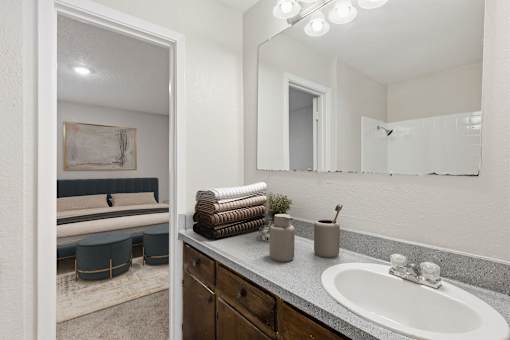 A bathroom with a white sink, a mirror, and a large mirror above the sink.