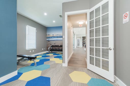 a corridor with doors and a gym with a blue and yellow carpet