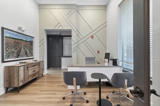 an office with a desk and chairs and a wall with a tv
