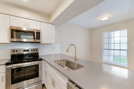 a kitchen with white cabinets and stainless steel appliances