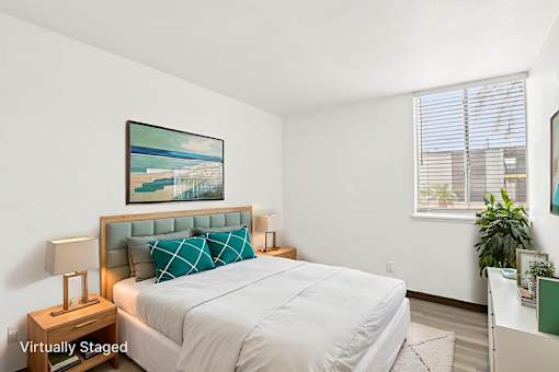A bedroom with a bed, nightstand, and a painting on the wall.