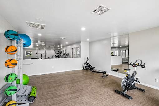 A gym with exercise equipment and a mirror on the wall.