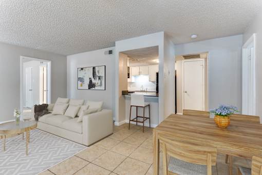 A living room with a couch, coffee table, and a dining table.