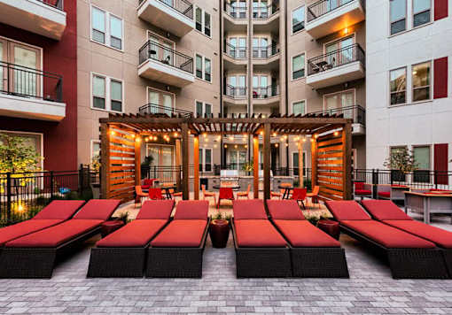 A patio with red sun loungers and a wooden pergola.