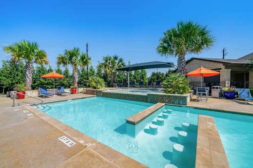 A pool with a water slide and a few chairs.