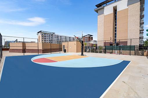 A basketball court with a blue surface and a red, white and blue circle in the middle.