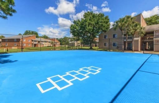 a large blue basketball court with apartments in the background
