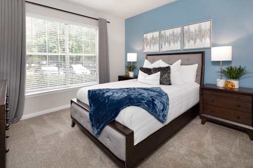A bedroom with a large bed and a window with blinds.