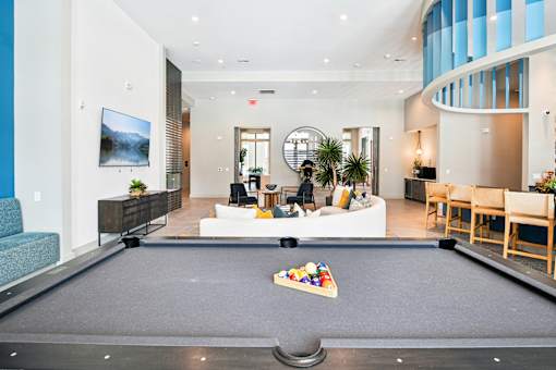 A pool table is in the middle of a room with a couch and a chair.