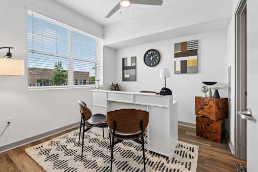 A room with a desk, chair, and a clock on the wall.