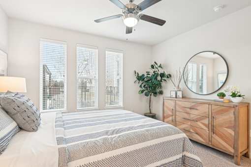 A bedroom with a bed, a dresser, and a ceiling fan.