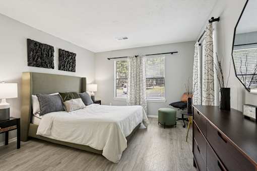 A bedroom with a large bed and a window with curtains.
