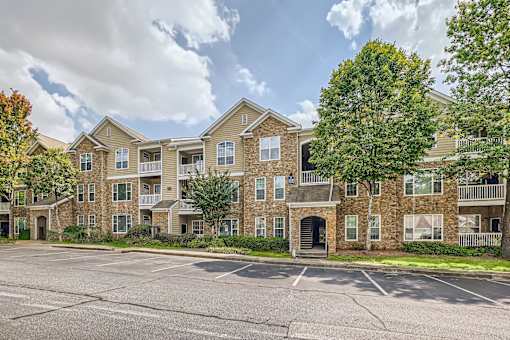 A large apartment complex with a parking lot in front.