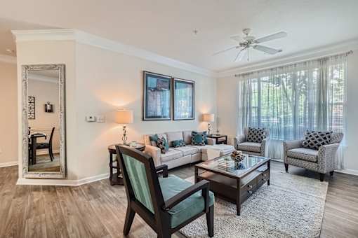 A living room with a chair, a sofa, a table, and a mirror.