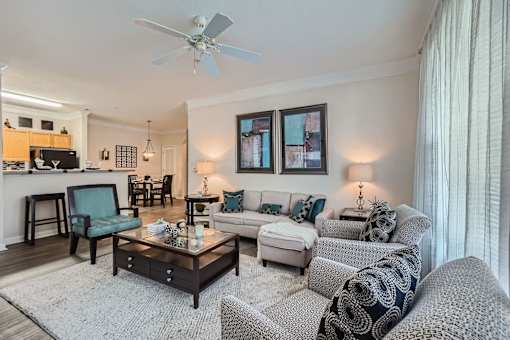 A living room with a white ceiling fan and a grey couch.