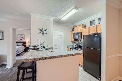 A kitchen with a black refrigerator and a counter with a brownish hue.