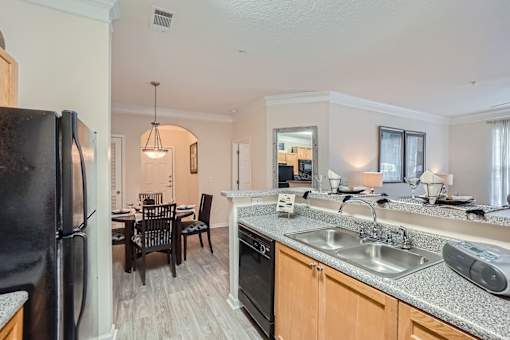 A kitchen with a black fridge, black oven, and a black dining table with chairs.