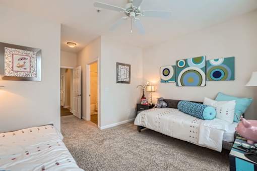 A bedroom with a bed, a couch, and a ceiling fan.
