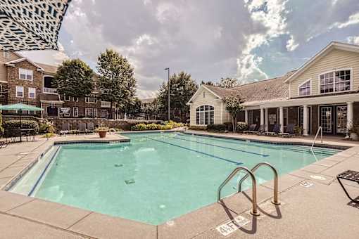 A large swimming pool surrounded by a concrete patio and a metal ladder.