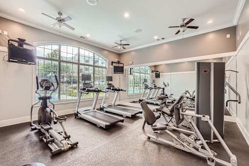 A spacious home gym with a television, exercise equipment, and a window.
