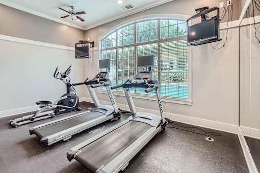 A home gym with treadmills and elliptical machines.