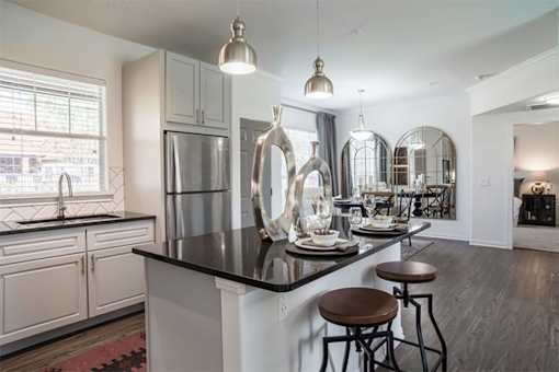 A modern kitchen with a black countertop and stainless steel appliances.