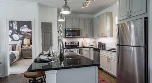 A modern kitchen with a stainless steel refrigerator and a black countertop.