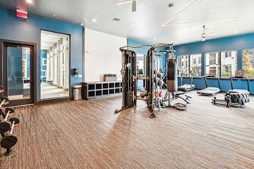 A gym with a variety of equipment including weights and cardio machines.