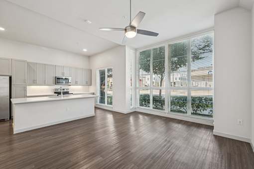 A spacious kitchen with a fan and wooden flooring.