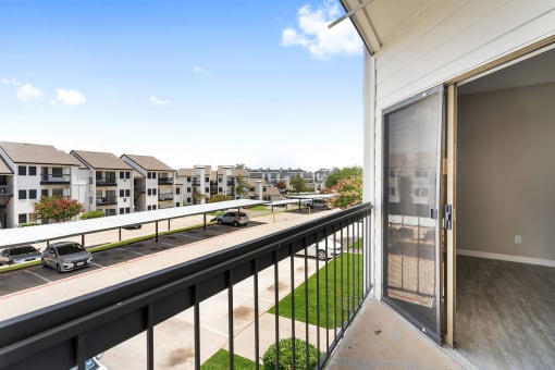 a balcony with a sliding glass door and a view of a parking lot