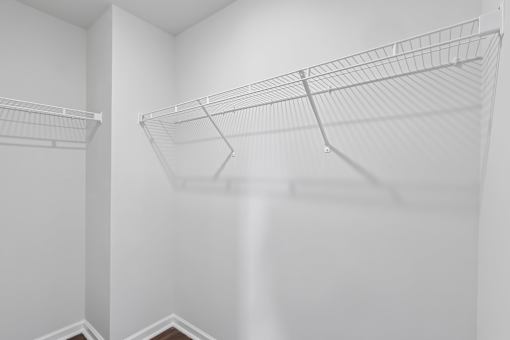Two empty wire shelves in a white room.