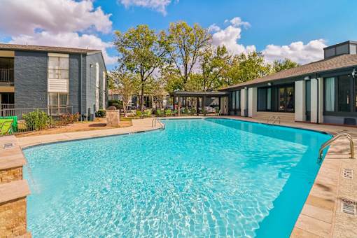 A large swimming pool in front of a building with a fence around it.