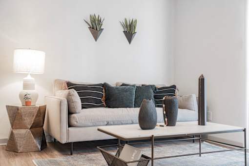 A living room with a grey couch, a white table, and a grey rug.