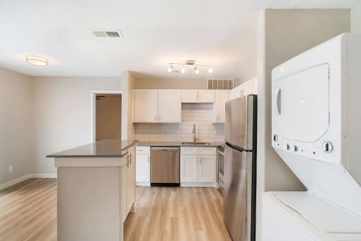 a kitchen with white cabinets and stainless steel appliances and a washer and dryer