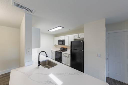 A kitchen with a sink and black appliances.