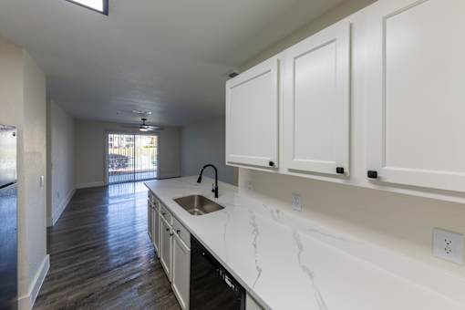 A kitchen with white cabinets and a marble countertop.