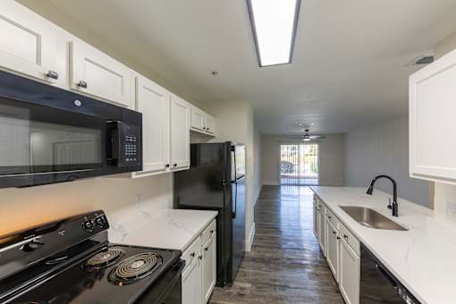A kitchen with black appliances and white cabinets.
