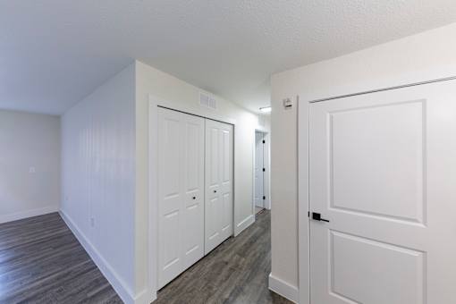 A hallway with white doors and wood floors.