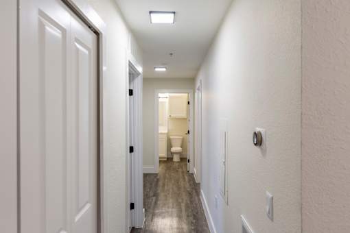 A long white hallway with doors on both sides and a light on the ceiling.