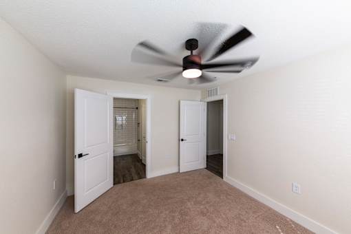 A room with a ceiling fan and two doors.