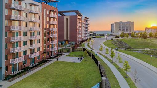 A sunset view of a residential area with apartment buildings and a road.