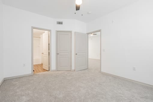 an empty living room with two doors and a carpeted floor