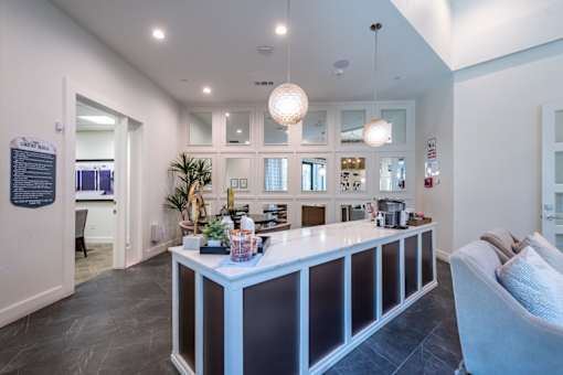 A reception area with a white reception desk and a couch.