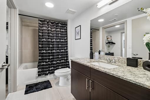 A bathroom with a white toilet, a sink, and a shower with a black and white curtain.